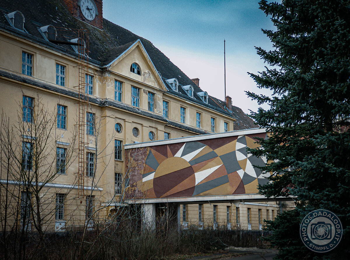 Edificio abbandonato con orologio e murale geometrico
