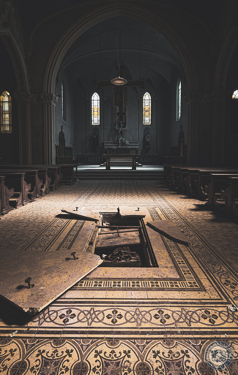 Chiesa abbandonata con pavimento decorato e botola aperta