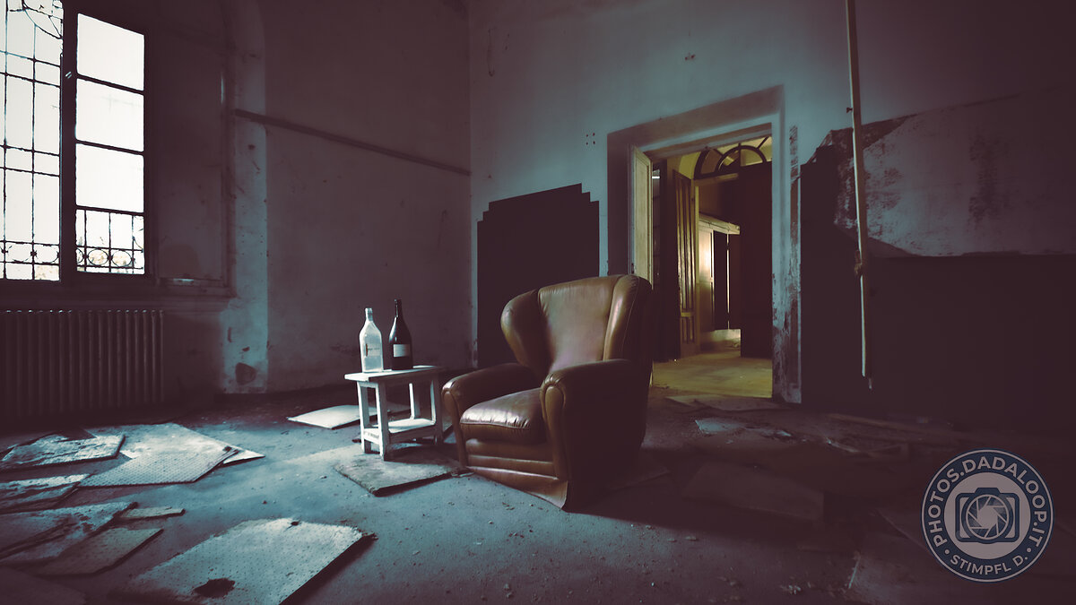 Poltrona e bottiglie in stanza abbandonata