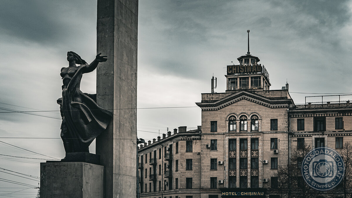 Statue and Chișinău Hotel under a leaden sky