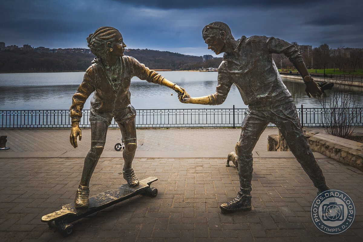 Sculptures of young people holding hands near the lake