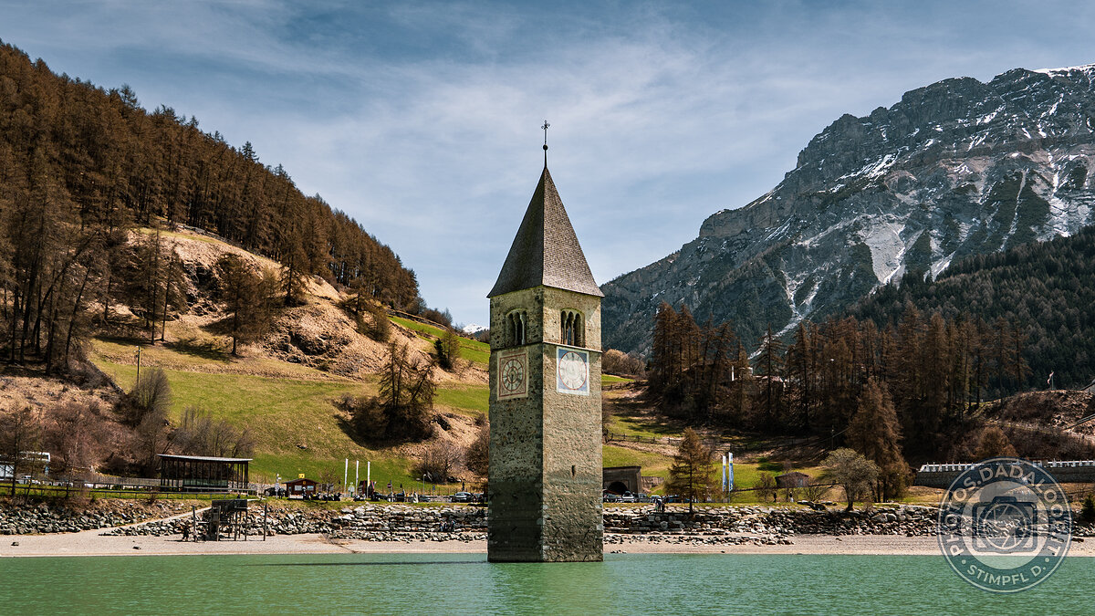 Campanile sommerso di Curon nel Lago di Resia con montagne innevate