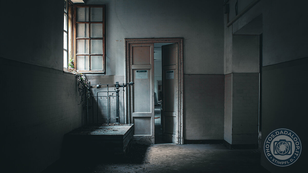 Corridoio abbandonato con finestra e porta socchiusa