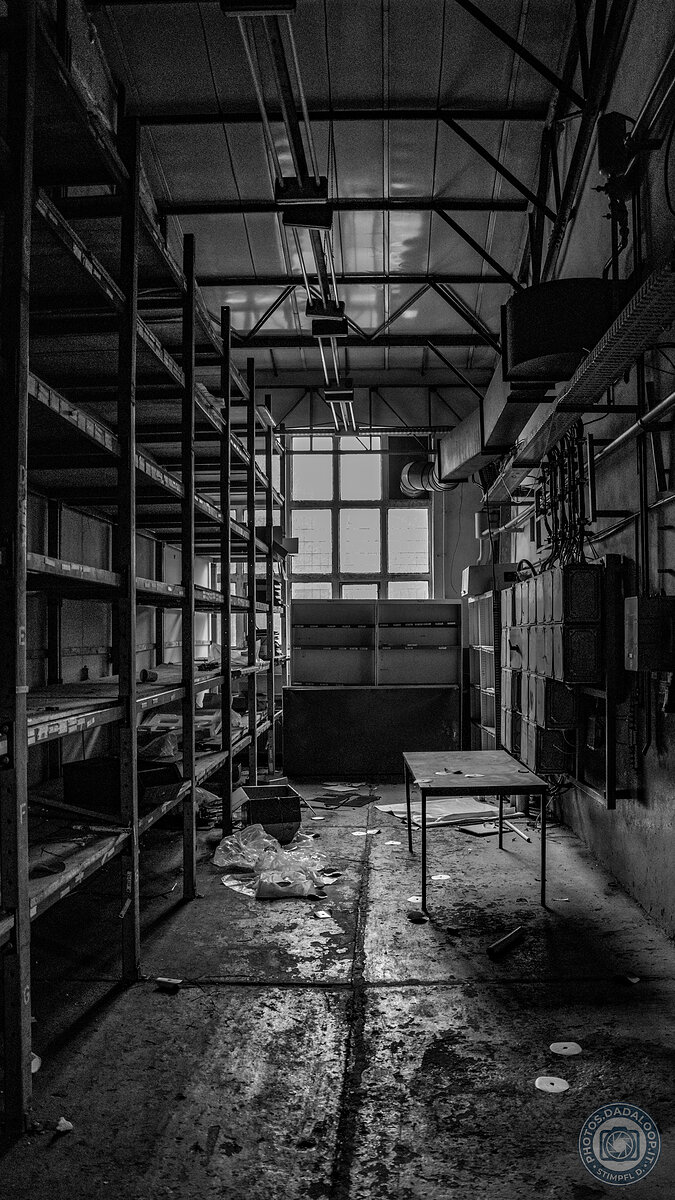 Interno spettrale di fabbrica abbandonata con scaffali e tavolo