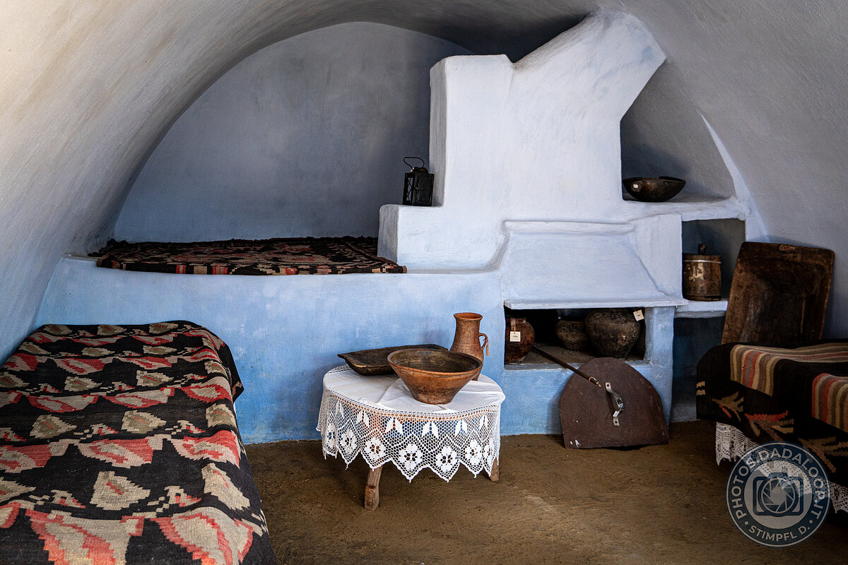 Interno di abitazione tradizionale con letto e oggetti d'uso quotidiano