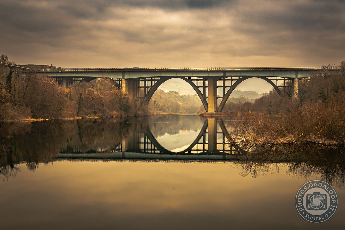 Symmetrical reflection of an arched bridge at sunset