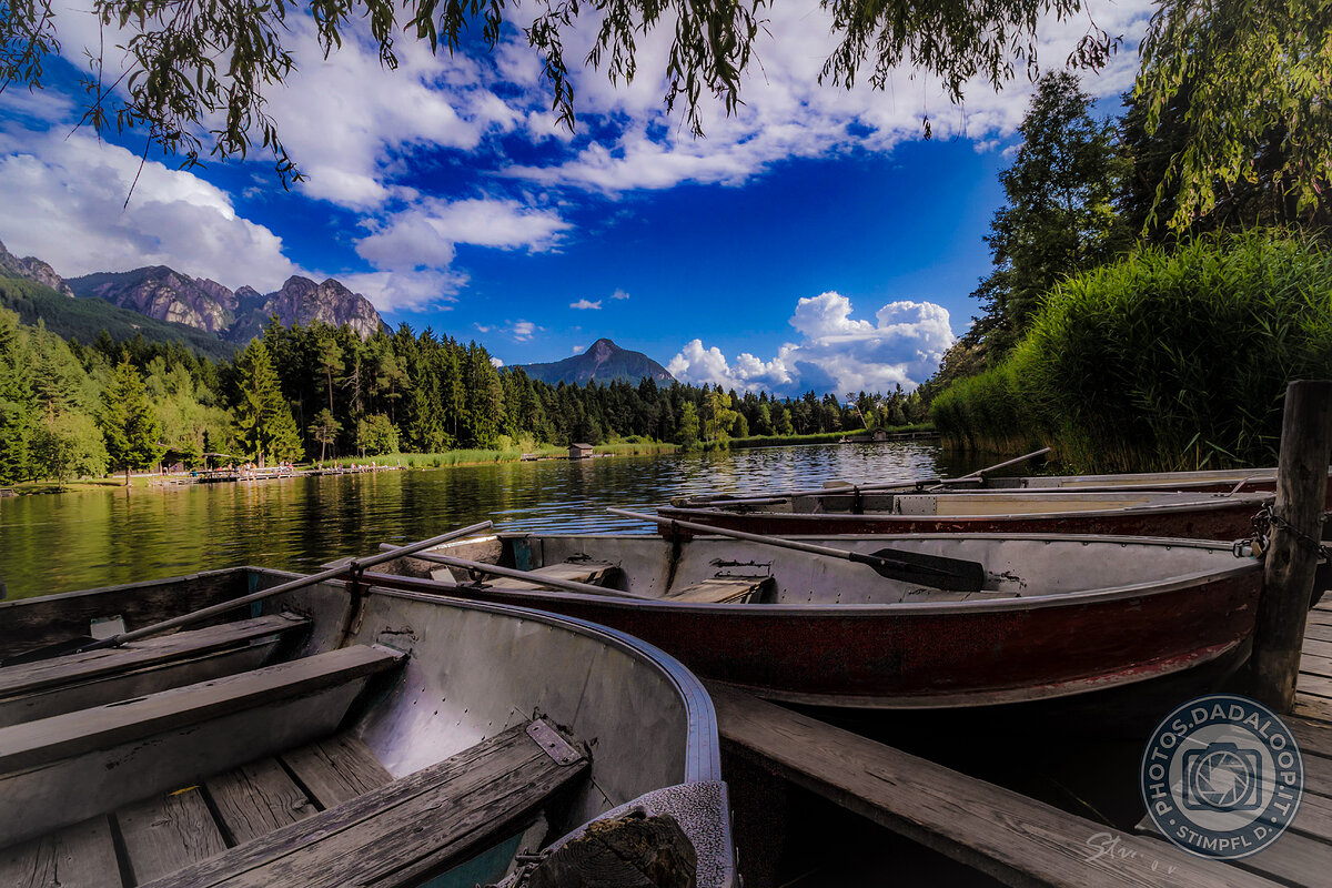 Boats moored on a mountain lake under a cloudy sky