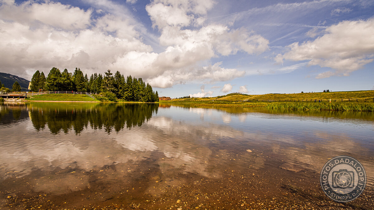 Reflections of clouds and trees in the alpine lake