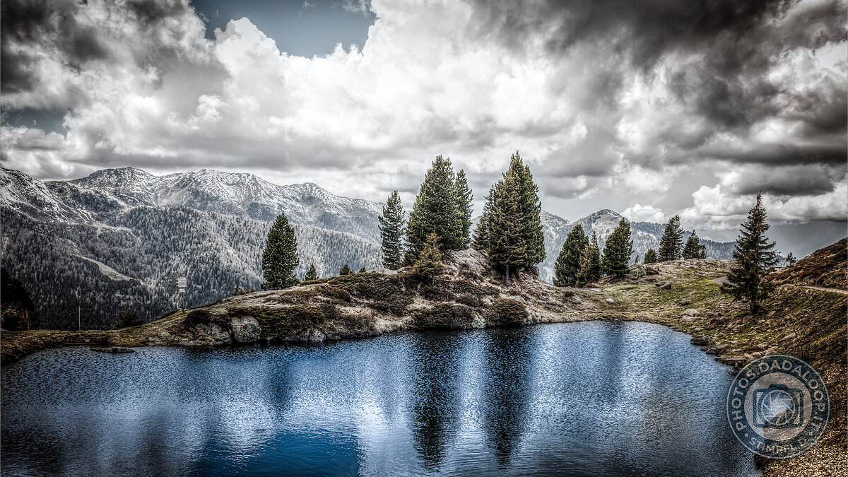 Riflessi montani in un lago alpino sotto un cielo nuvoloso