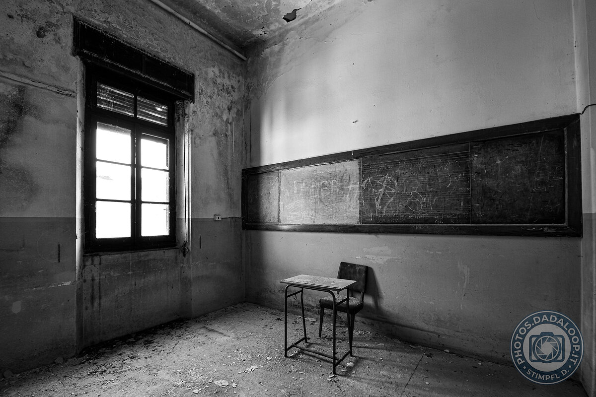 Abandoned classroom: dim light on desk and blackboard