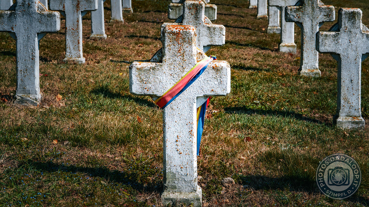 Croci di pietra in un cimitero abbandonato, con nastro tricolore