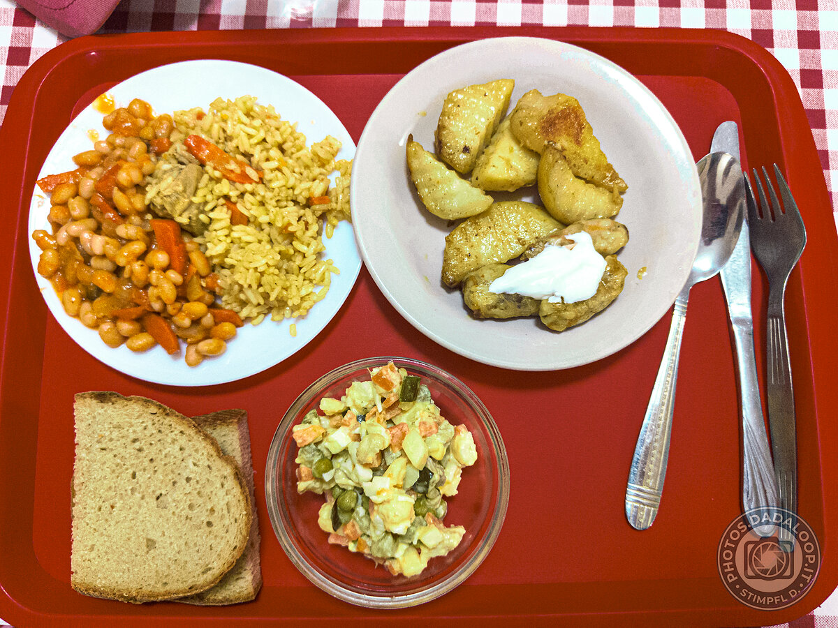 Pasto su vassoio rosso: riso, fagioli, patate e insalata russa